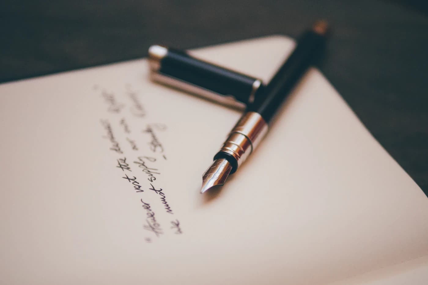 A fountain pen resting on handwritten pages.