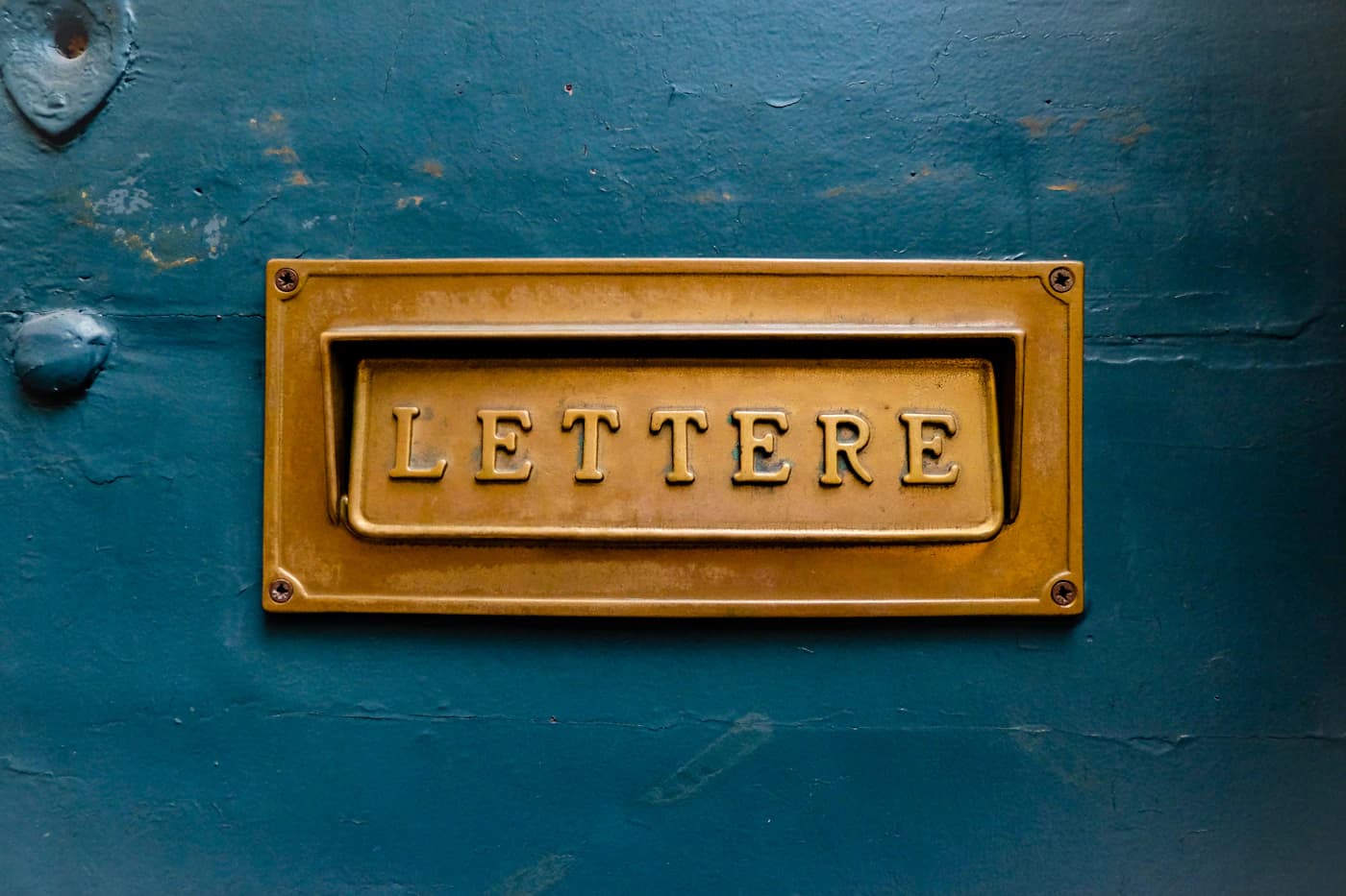 A brass letters slot on a painted door.