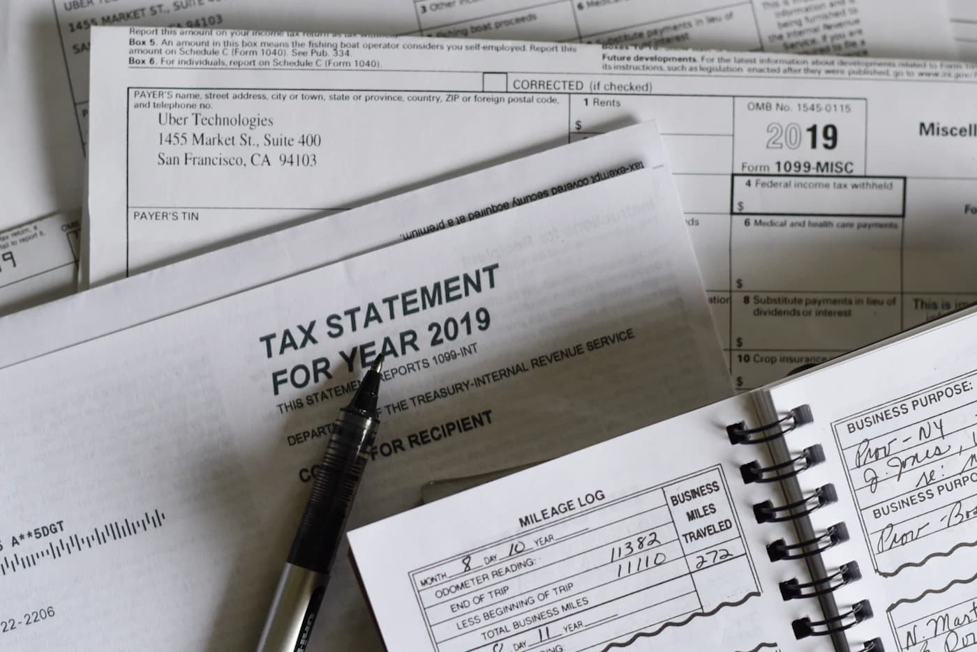 A tax statement and 1099 forms laid out on a desk.