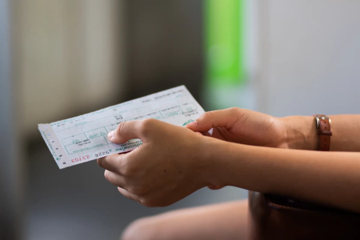 A printed paycheck held in hand, what the employee receives at the end of the cycle.
