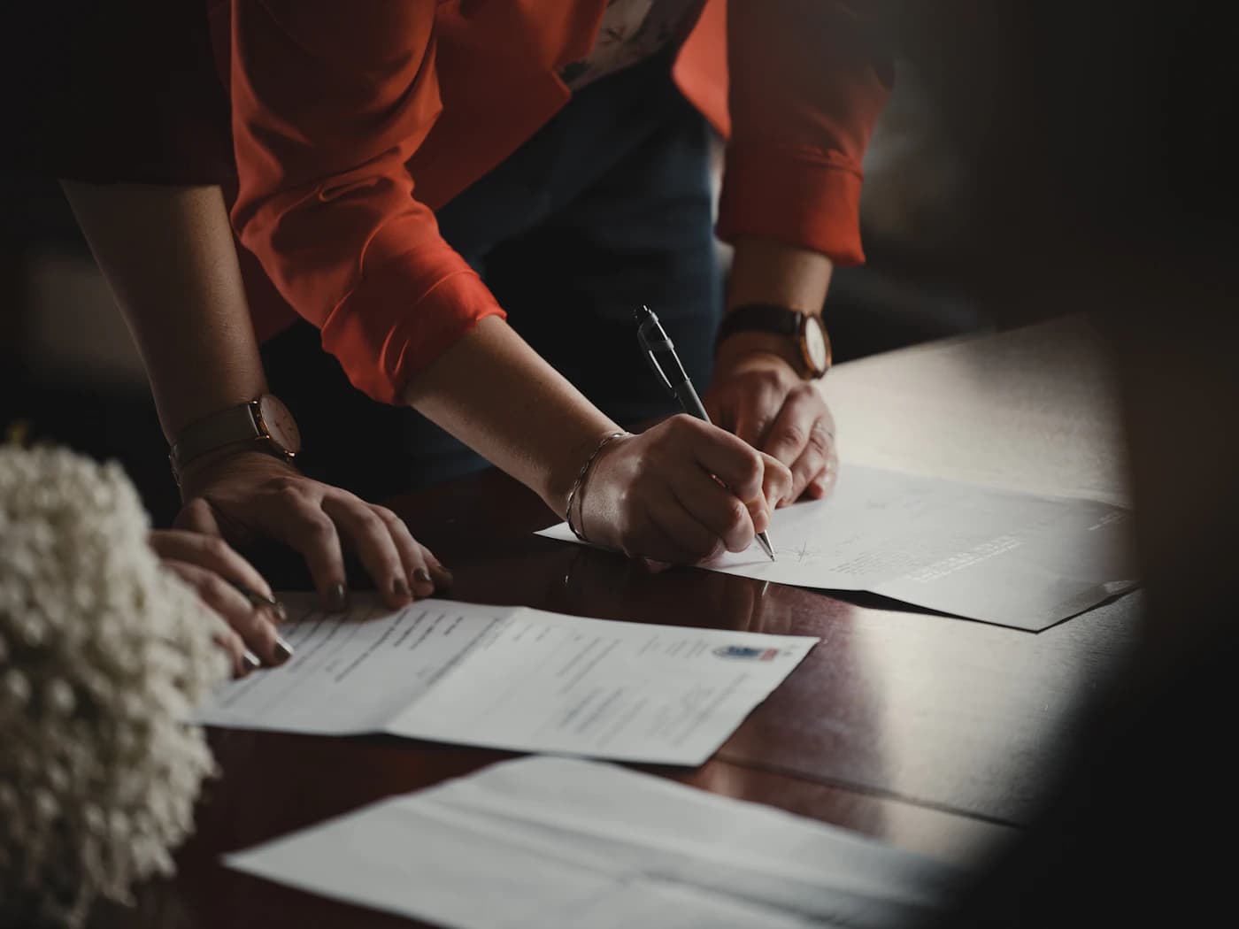 A hand signing an official document with a fountain pen.