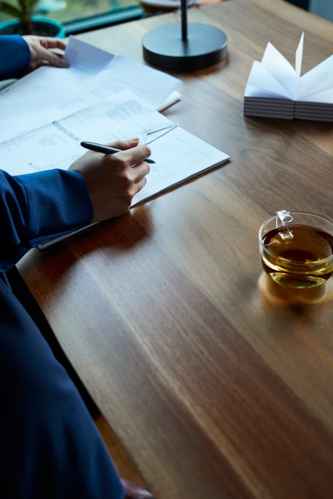 Hands at a walnut desk preparing the filing.