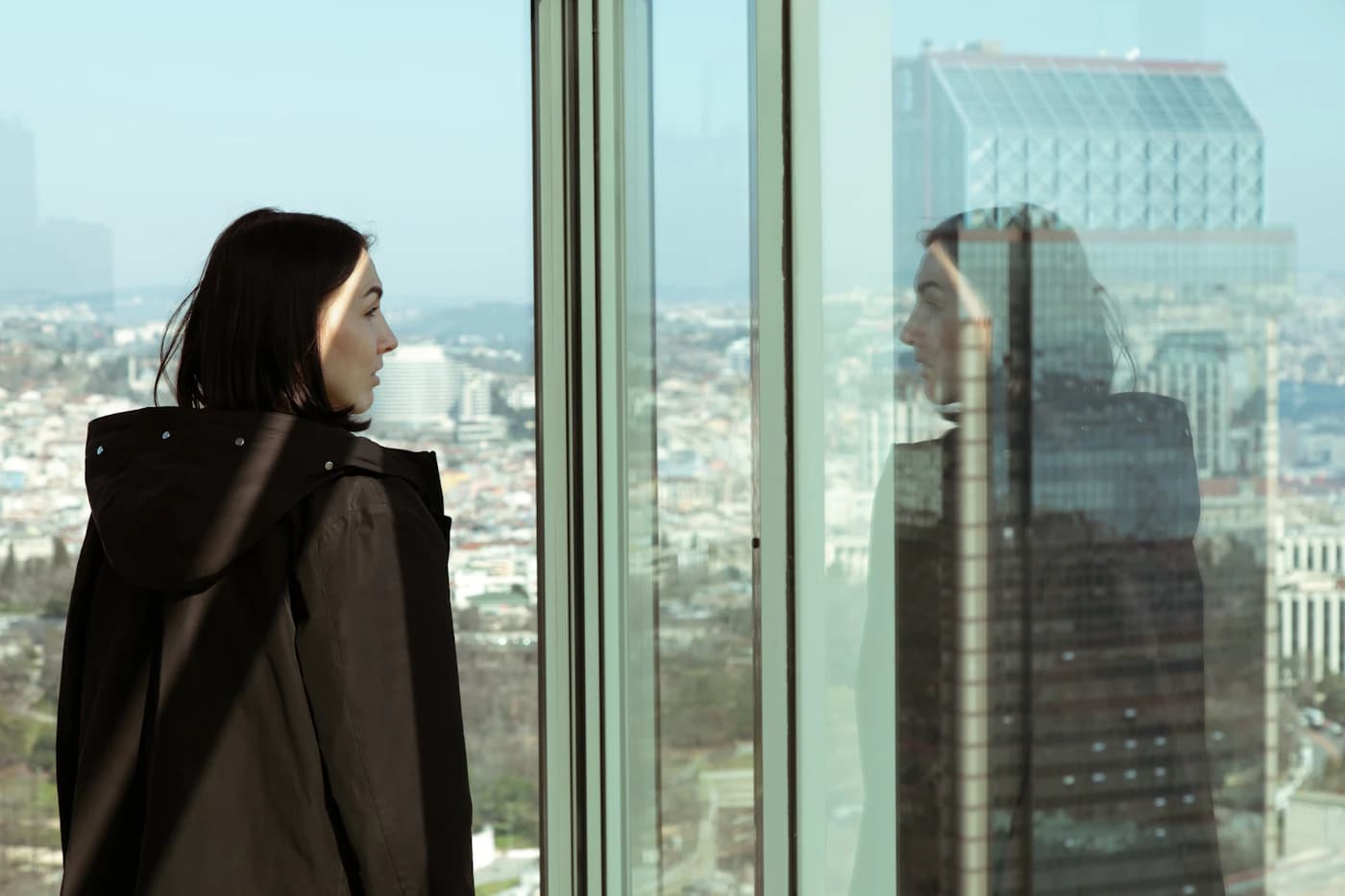 A founder at a high-rise window, looking out over a city where she will build her company.