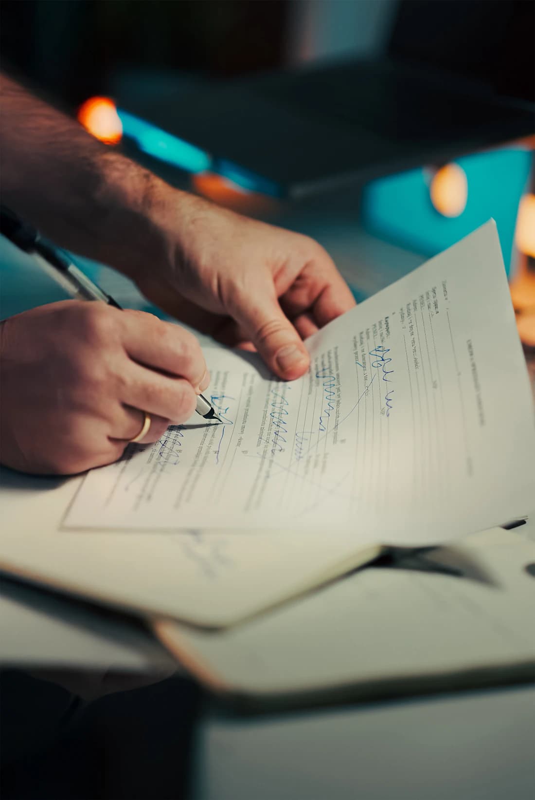 Hands drafting a document by warm light.